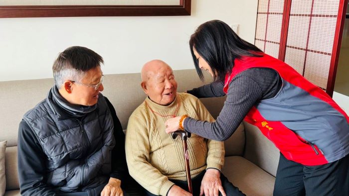 《圖說》王玟琳組長(右)代表致贈金壽桃，親自為郭爺爺(中)戴上，向郭爺爺祝賀壽誕。〈新北榮服處提供〉