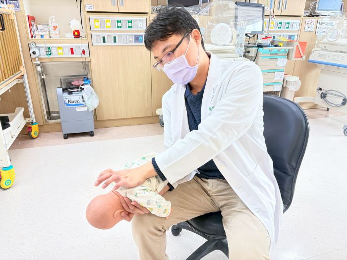 《圖說》邱俊哲醫師示範一歲以下嬰兒「拍背壓胸法」,背部拍擊5次、正面壓胸5次,反覆進行至異物排出。〈土城醫院提供〉